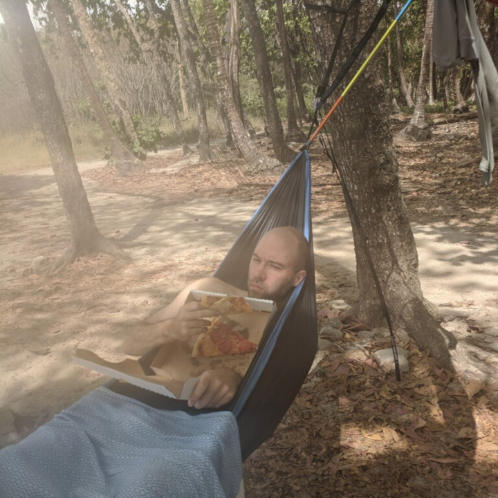 Peter in hammock eating pizza